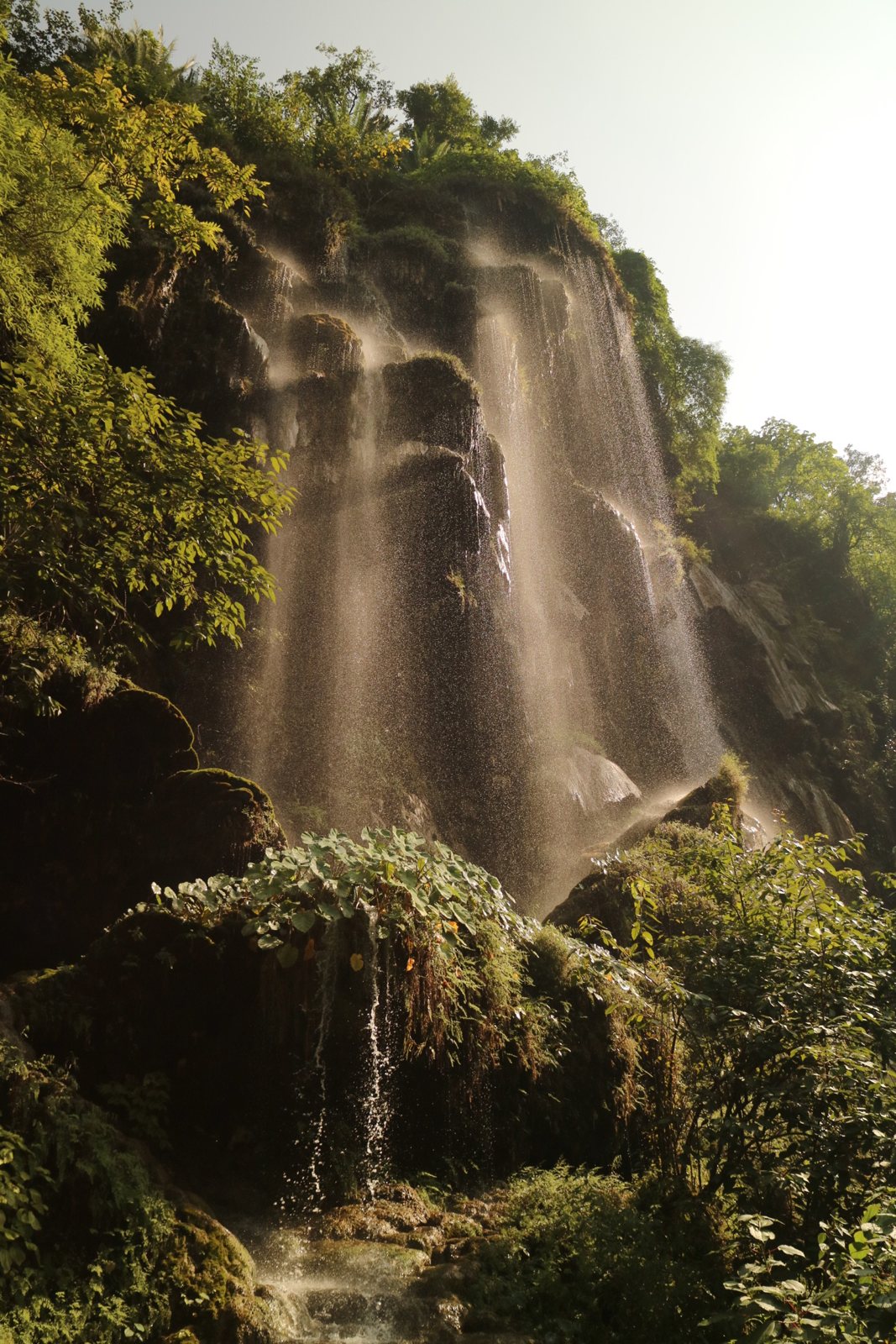 Sunlit waterfall over mossy rock