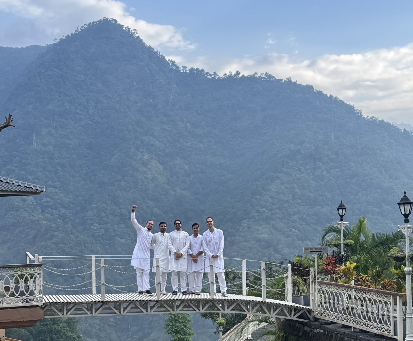 Five men in white kurtas on a bridge in the mountains